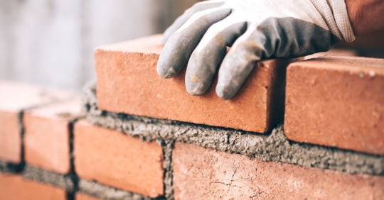 Close up of industrial bricklayer installing bricks on construction site